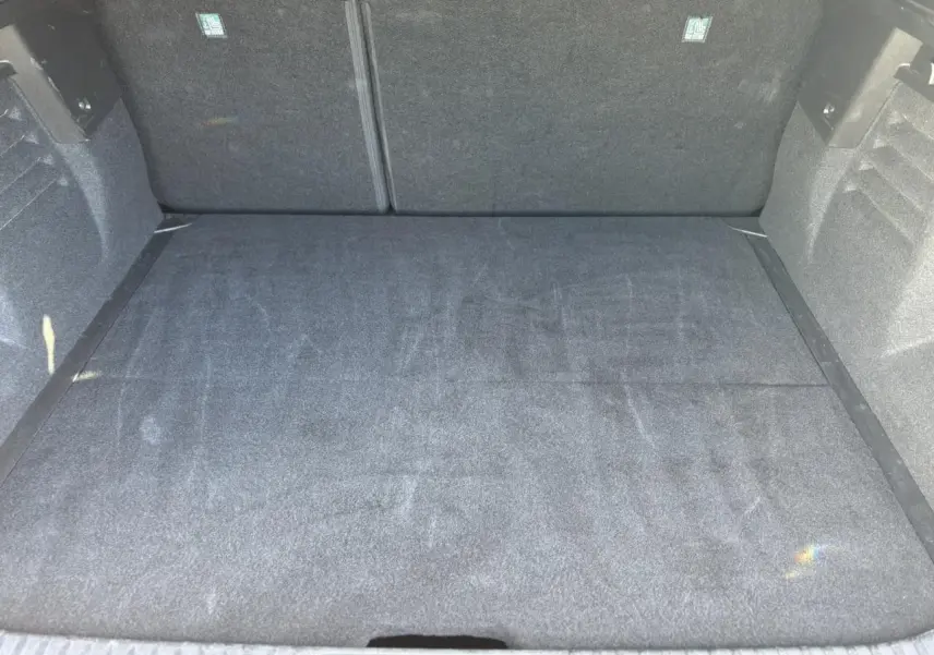 Vue intérieure du coffre spacieux et propre du Renault Symbioz E-Tech Full Hybrid 145 Iconic, revêtement gris foncé.