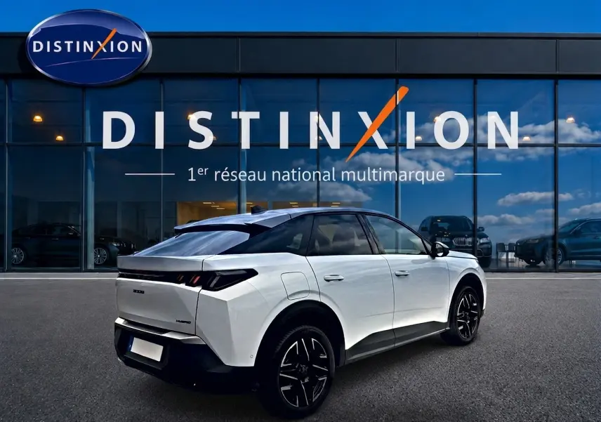 Vue 3/4 arrière droite d’un Peugeot 3008 blanc avec toit noir, jantes alu noires et feux arrière LED, devant une vitrine Distinxion.
