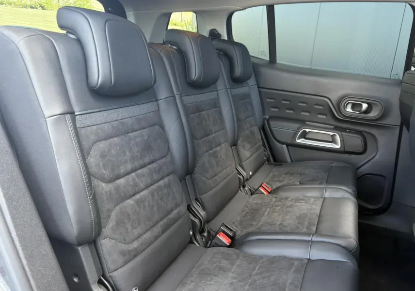 Vue latérale des trois sièges arrière en Alcantara noir du Citroën C5 Aircross 2025, avec portes et ceintures visibles.