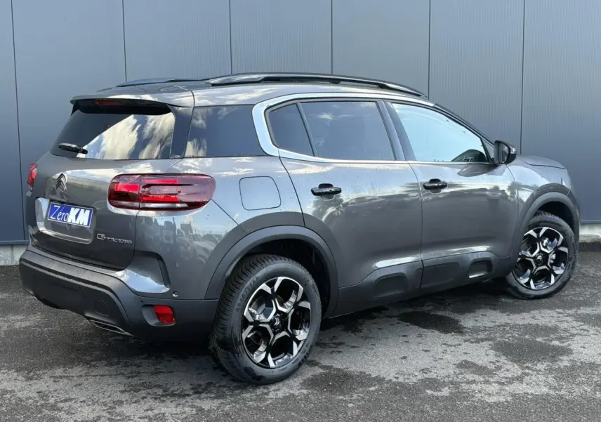 Citroën C5 Aircross gris Platinium en 3/4 arrière droit, avec jantes bi-ton et toit ouvrant panoramique visible.