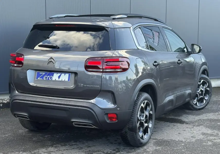 Vue 3/4 arrière droite d'un Citroën C5 Aircross gris Platinium avec jantes alliage bi-ton et hayon électrique.