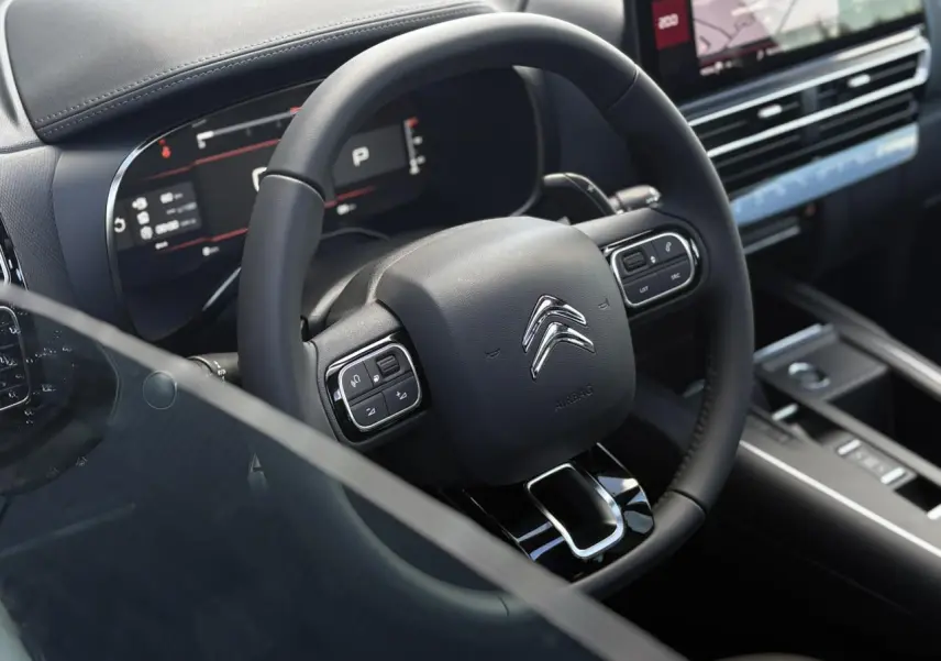 Vue rapprochée du volant noir de la Citroën C5 Aircross 2025 avec commandes intégrées et tableau de bord numérique.