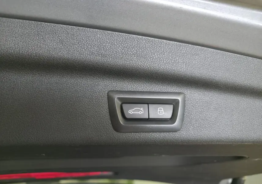 Boutons de commande du hayon et verrouillage intégrés au panneau intérieur du coffre d'une BMW Série 2 gris 3/4 arrière.