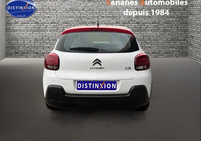 Vue arrière d'une Citroën C3 2021 blanche avec toit rouge, feux arrière foncés et logo distinctif Citroën.