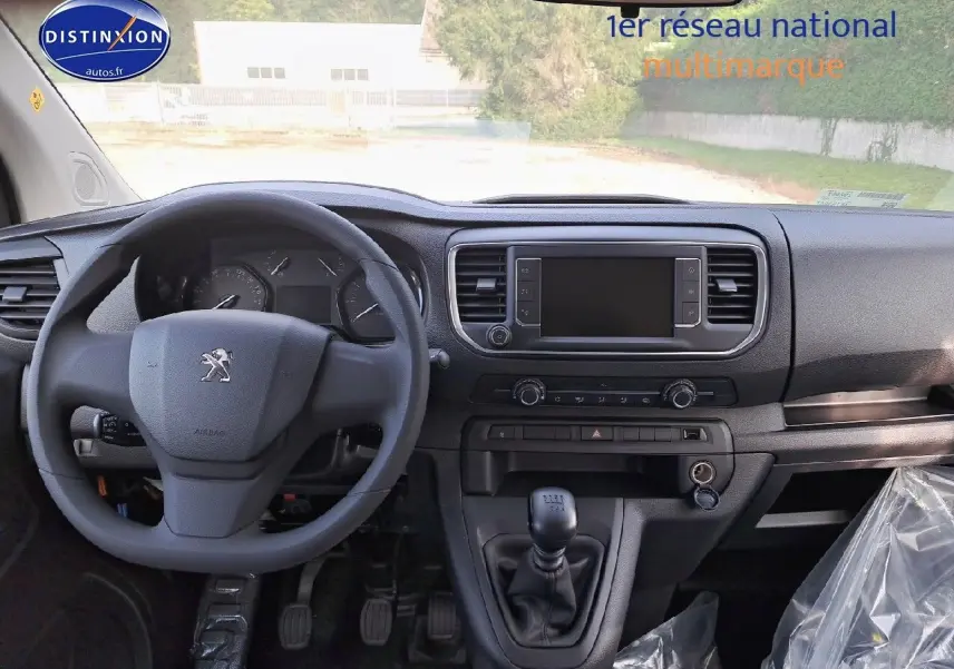 Vue intérieure avant du Peugeot Expert Blanc Kaolin 2023, tableau de bord avec volant, écran tactile et levier de vitesse manuel.