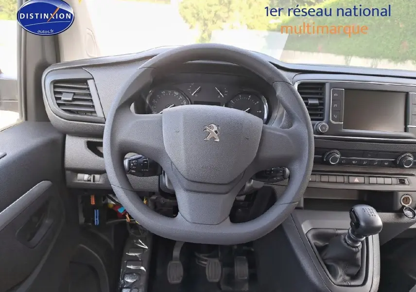Vue intérieure centrée sur le volant Peugeot et la console avec levier de vitesses manuelle du Expert blanc Kaolin 2023.