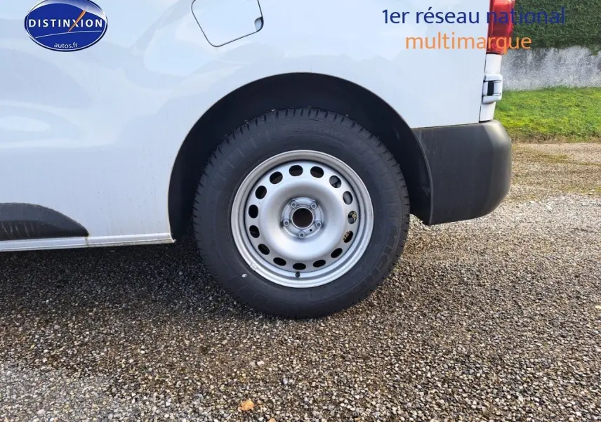 Gros plan sur la roue arrière droite d’un Peugeot Expert Blanc Kaolin, avec pare-chocs noir et carrosserie visible.
