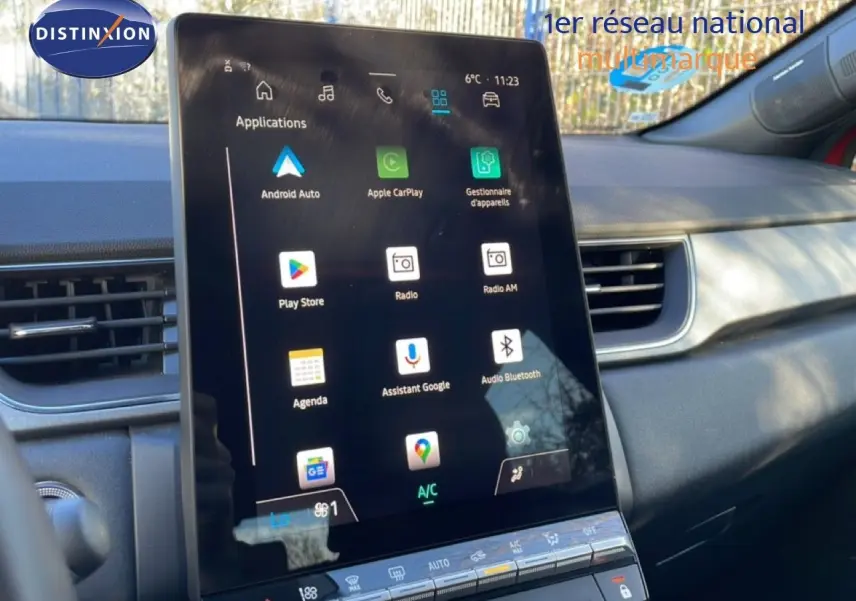 Vue intérieure centrée sur l’écran tactile vertical du tableau de bord du Renault Captur rouge désir métal avec toit noir.