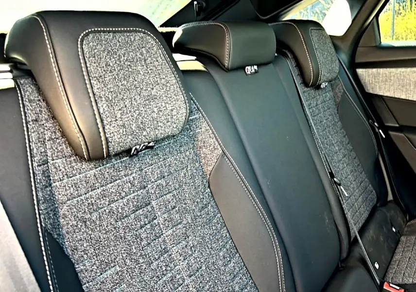 Vue rapprochée de la banquette arrière en tissu gris et cuir noir du Peugeot 3008 1.2 Hybrid 145 Allure 2025.