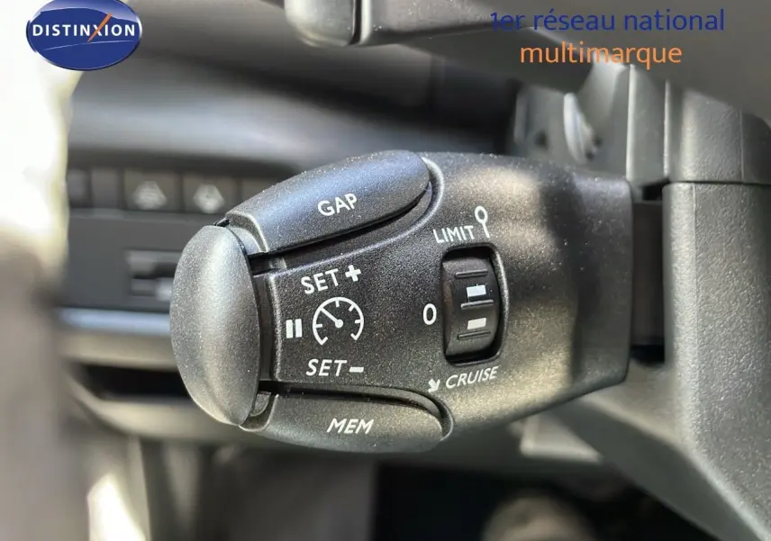 Gros plan sur la commande de régulateur de vitesse du Citroën C5 Aircross 2025, intérieur noir avec détails blancs.