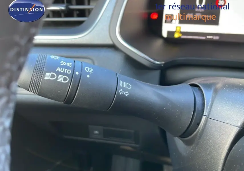 Gros plan sur la commande des phares à gauche du volant dans l’habitacle du Renault Captur gris Rafale métal toit noir.