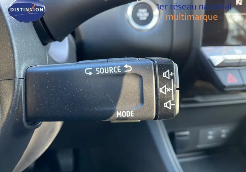 Gros plan sur la commande au volant du Renault Captur 2025 gris Rafale métal avec toit noir, montrant les boutons source et mode.