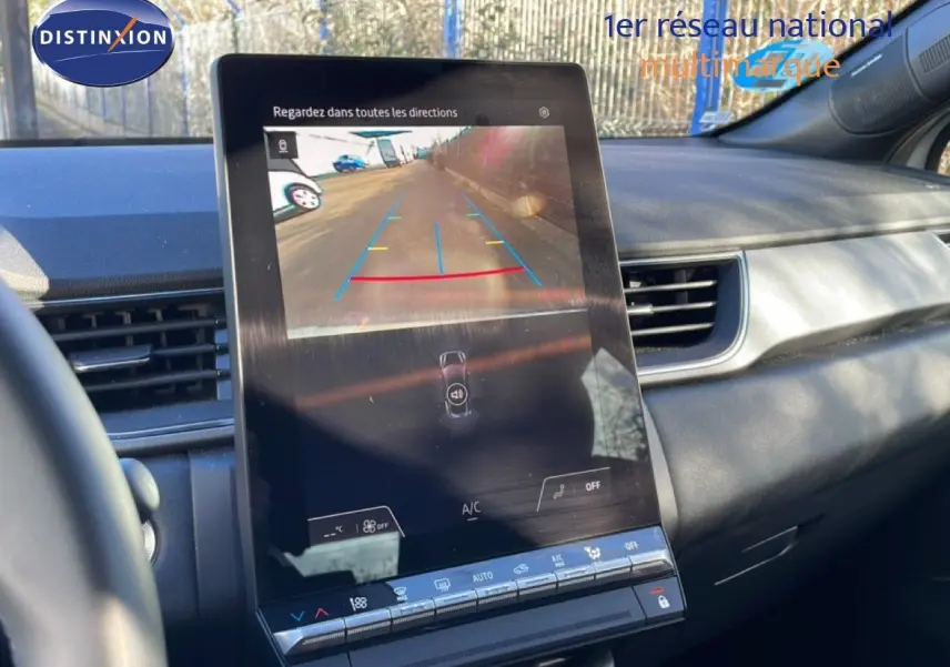 Vue intérieure du tableau de bord du Renault Captur 2025, écran central affichant la caméra de recul avec commandes climatisation en dessous.