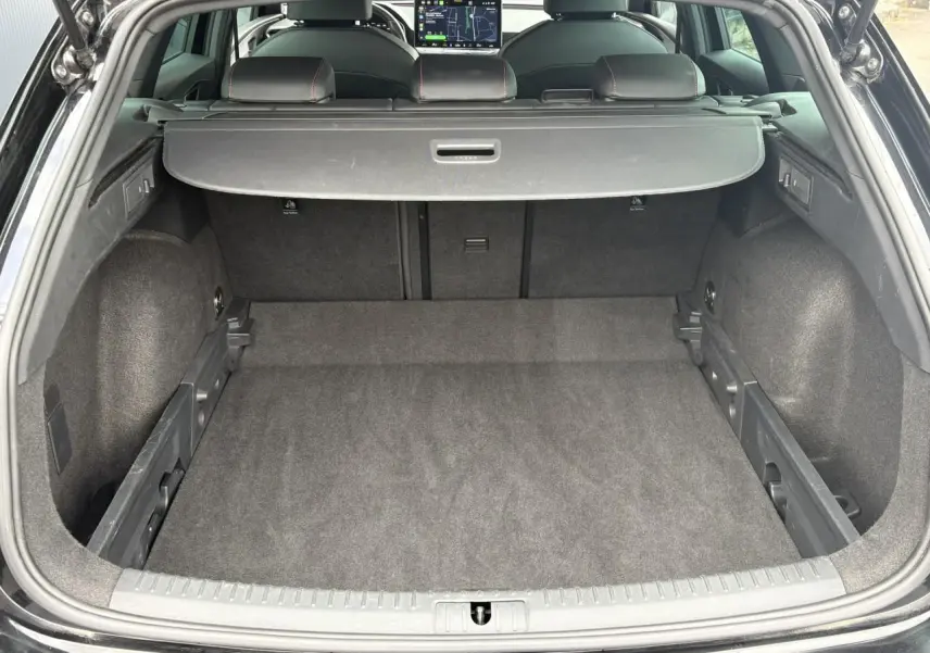 Coffre ouvert vu de l'arrière d'une SEAT Leon noir Minuit, montrant un espace de chargement propre et bien agencé.
