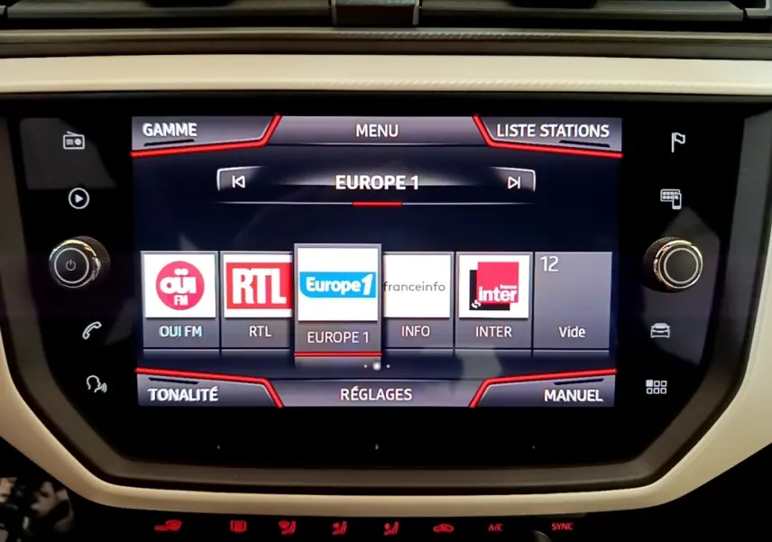Écran tactile central du tableau de bord du SEAT Arona 2019 affichant les stations radio, entouré de commandes physiques.