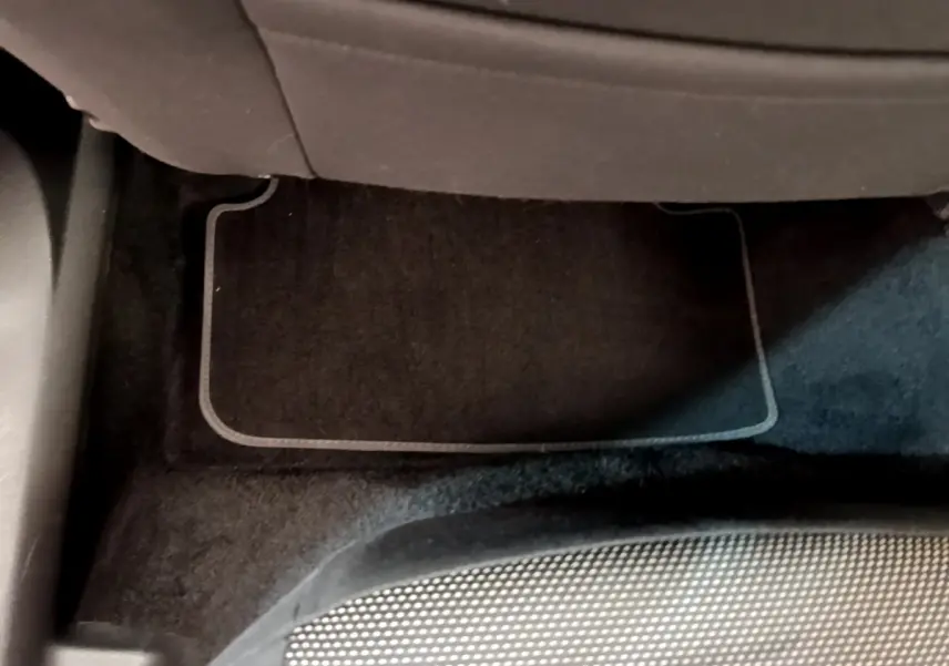 Vue rapprochée du tapis de sol noir sous le siège arrière du SEAT Arona gris clair, intérieur sobre.
