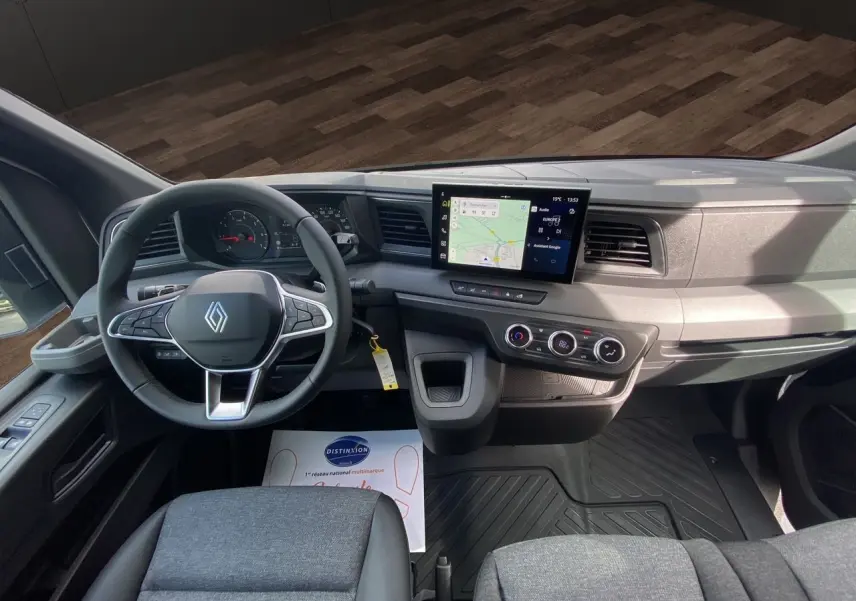 Vue intérieure avant du Renault Master 2025, tableau de bord gris avec écran tactile et volant multifonction noir.