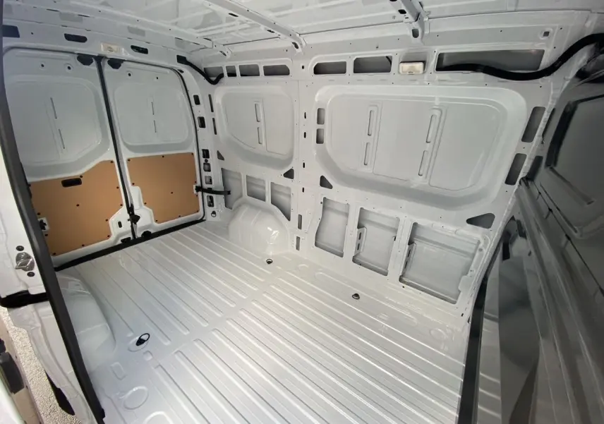 Intérieur arrière vide du Renault Master blanc, vue plongeante montrant l’espace de chargement et les portes ouvertes.