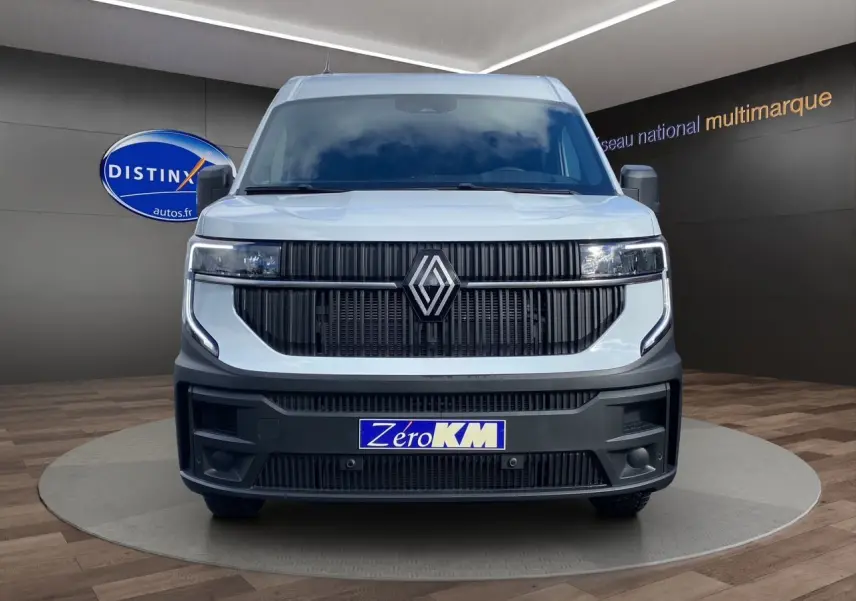 Vue avant d’un Renault Master blanc 2025 avec calandre noire et logo centré, sur fond intérieur showroom.