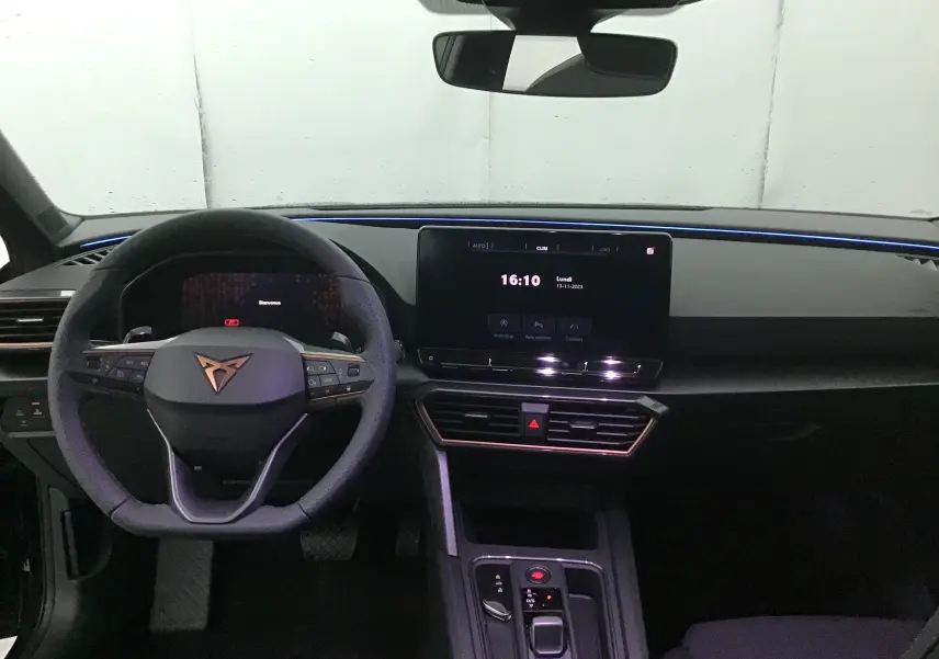 Intérieur noir de la CUPRA Leon 2023 vu de face, avec volant au logo Cupra et écran tactile central allumé.