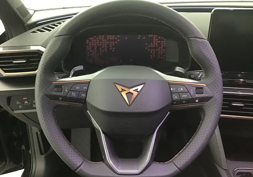 Volant en cuir perforé avec logo Cupra cuivré, tableau de bord numérique et partie centrale noire du Cupra Leon 2023.