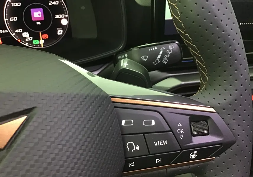 Gros plan sur le volant noir perforé de la CUPRA Leon 2023 avec commandes multifonctions et tableau de bord digital.
