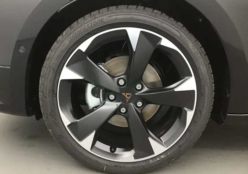 Gros plan sur la jante noire et argentée de 18 pouces avec logo Cupra sur un véhicule noir.