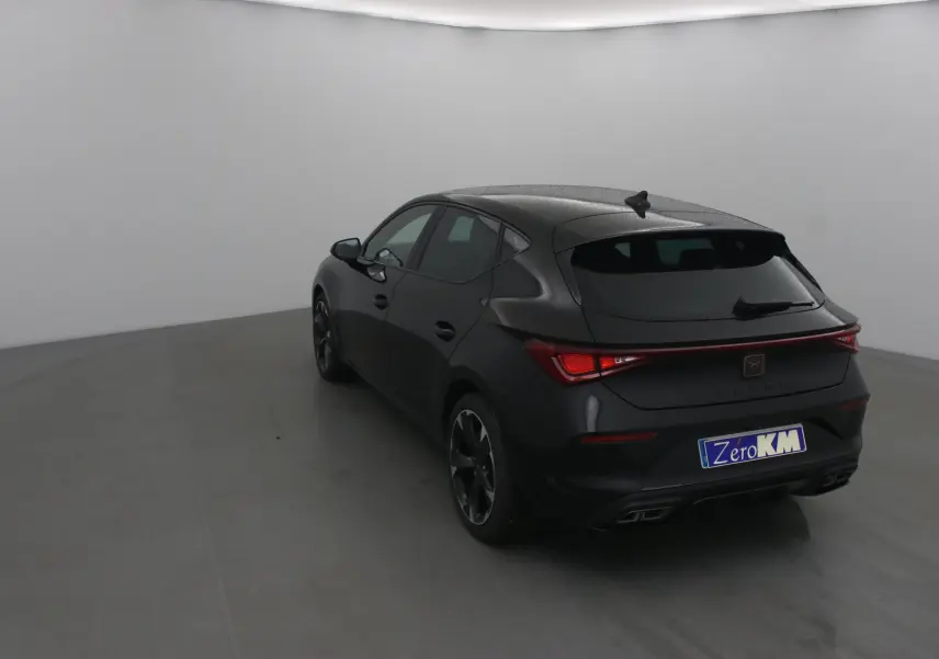 Vue 3/4 arrière droite d'une CUPRA Leon noire 2023 avec feux arrière LED et double sortie d'échappement intégrée.