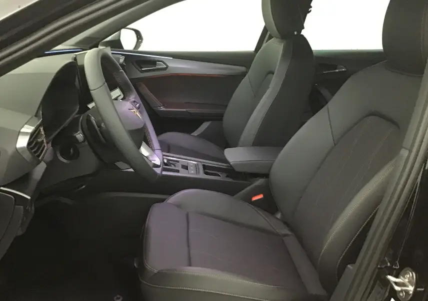 Vue intérieure côté conducteur de la CUPRA Leon noire 2023, sièges en cuir et tableau de bord digital moderne.
