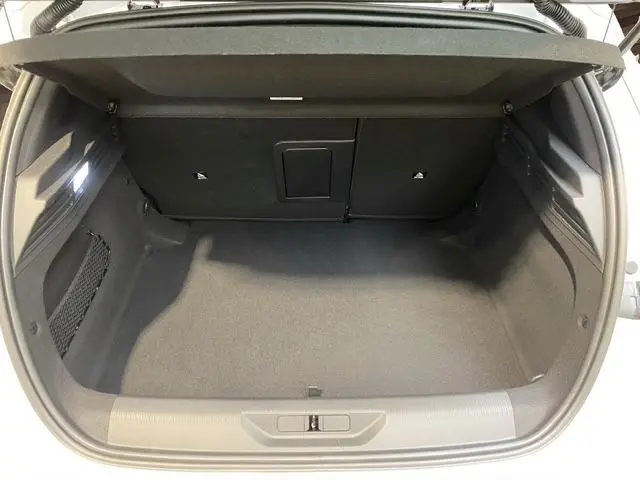 Vue intérieure du coffre spacieux et propre de la Peugeot 308 blanche, avec banquette arrière rabattable visible en arrière-plan.