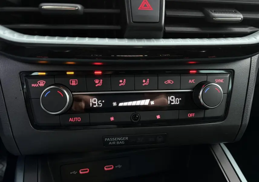 Gros plan sur la commande de climatisation automatique bi-zone du SEAT Arona gris, avec affichage digital et boutons rétroéclairés.