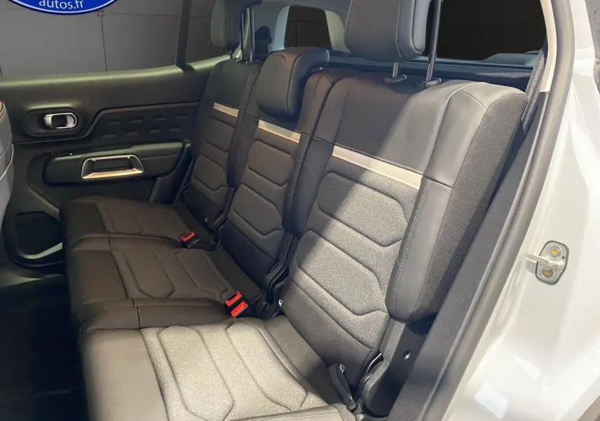 Vue intérieure sur la banquette arrière noire et grise du Citroën C5 Aircross blanc, porte arrière droite ouverte.