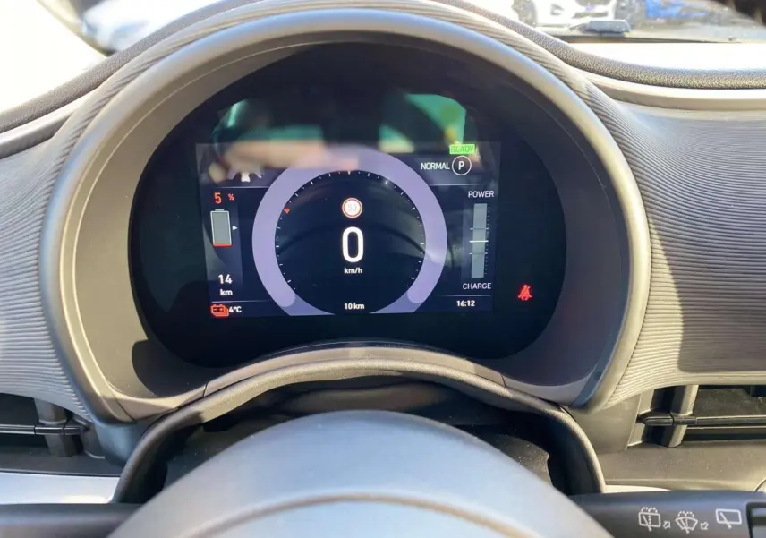 Vue rapprochée du tableau de bord numérique de la Fiat 500 électrique noire, affichant la vitesse et l'autonomie restante.