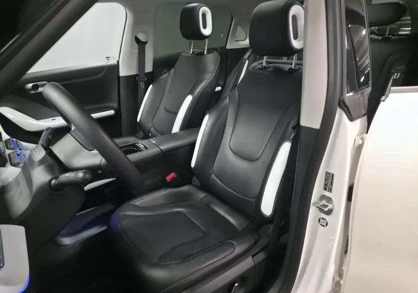 Intérieur côté conducteur d'une Smart #1 blanche 2024 avec sièges cuir noirs et inserts blancs, ambiance lumineuse bleue.