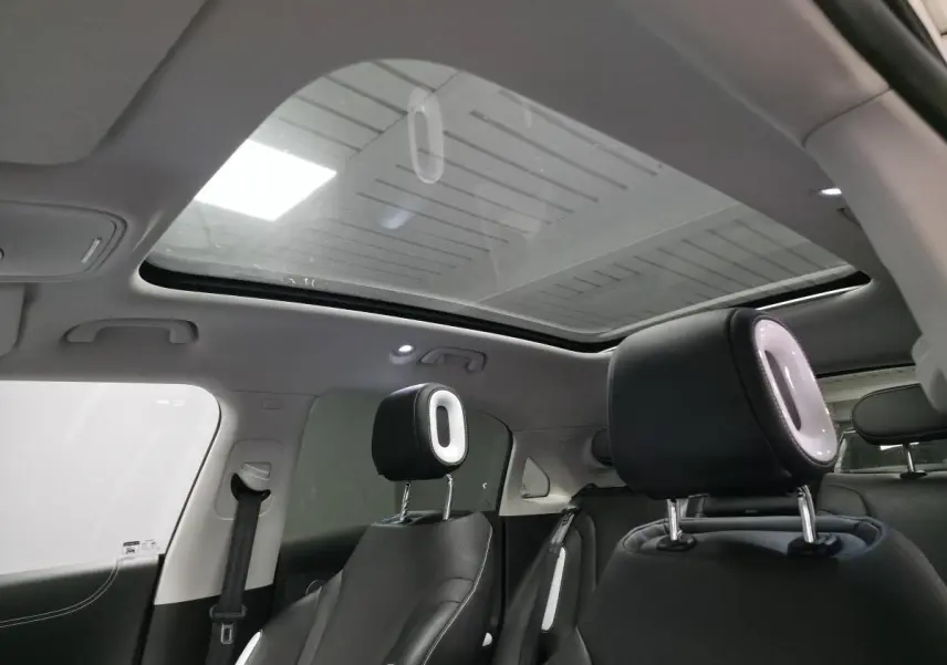 Vue intérieure arrière du Smart #1 blanc 2024, avec toit panoramique en verre et appuie-têtes noirs éclairés.