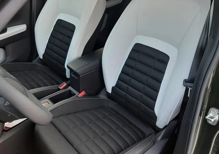 Vue rapprochée des sièges avant bicolores noir et blanc du Citroën C3 Aircross hybride 2026, porte ouverte côté droit.