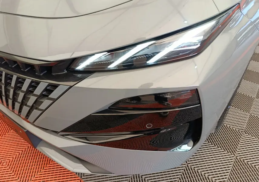 Gros plan sur l'avant droit gris foncé de la Peugeot 308 2026, mettant en valeur le phare LED et la calandre distinctive.