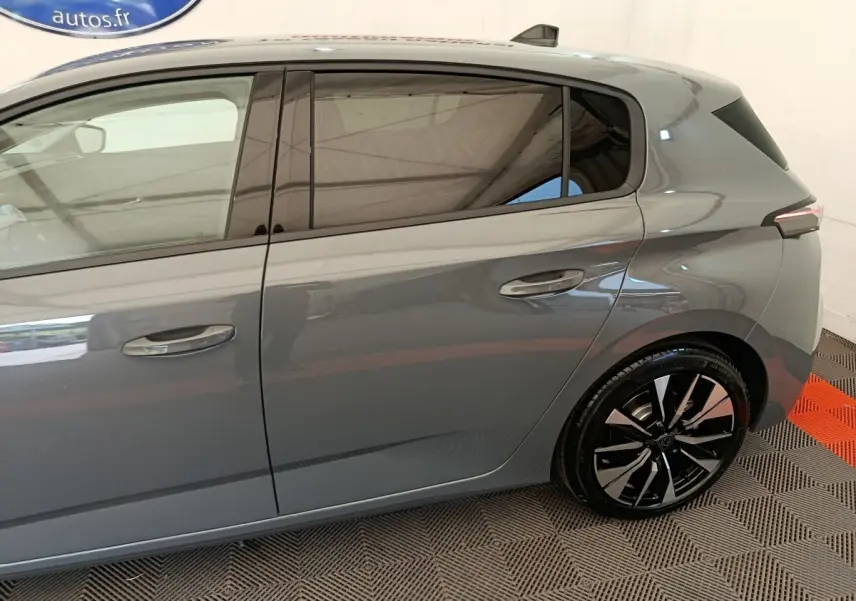Vue latérale droite d'une Peugeot 308 gris foncé, mettant en valeur les jantes alliage et les vitres teintées.