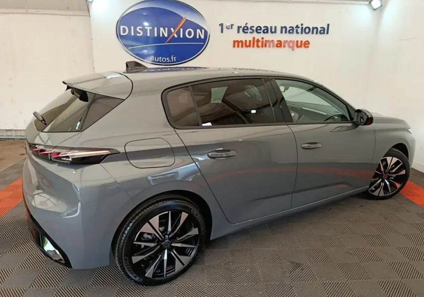 Peugeot 308 BlueHDi 130 en gris foncé vue 3/4 arrière droit, avec jantes noires et feux arrière LED fins.