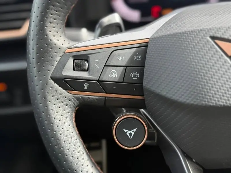 Gros plan sur le volant perforé du CUPRA Formentor 2025 avec commandes intégrées et détails cuivrés.
