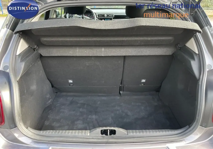 Coffre ouvert d'une Citroën C3 gris platinium métal, vue arrière montrant l'espace de chargement et l'intérieur du véhicule.