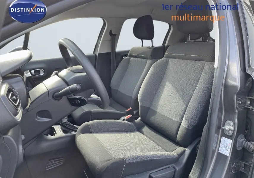 Intérieur avant droit de la Citroën C3 gris platinium métal 2023 avec sièges tissu gris et volant multifonction.