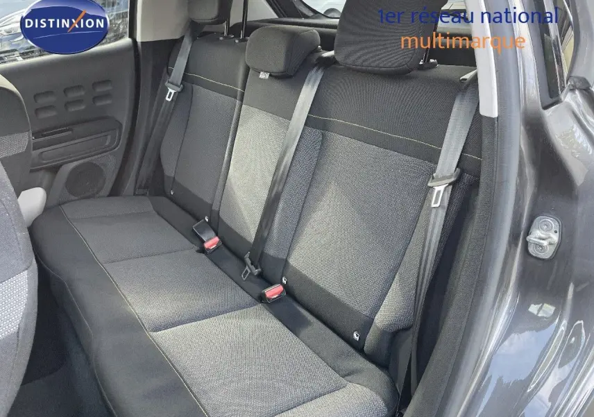 Vue intérieure côté gauche des sièges arrière en tissu gris noir d'une Citroën C3 gris platinium 2023 avec ceintures de sécurité visibles.