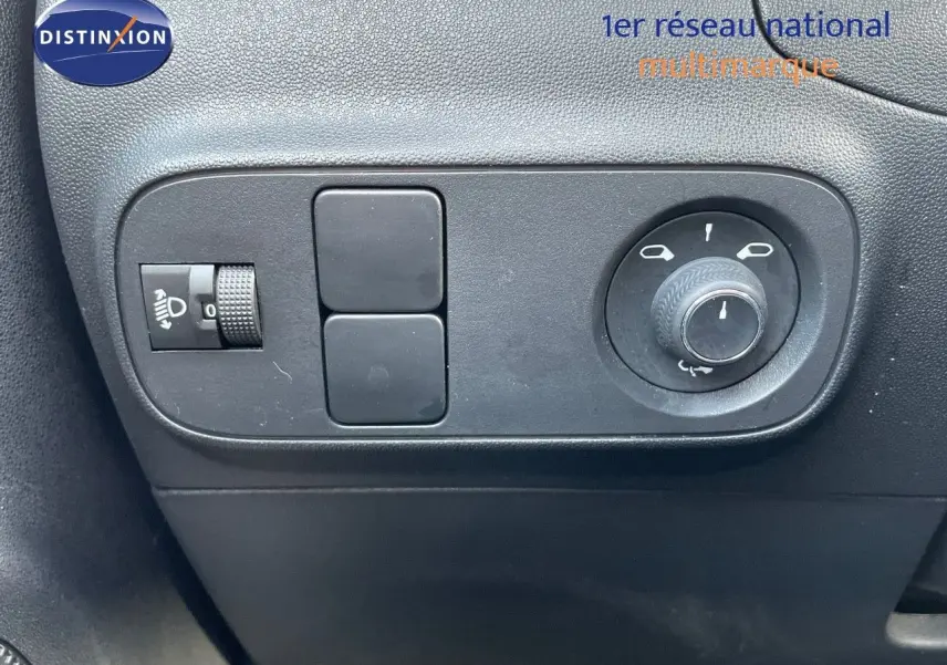 Gros plan sur les commandes de réglage des rétroviseurs et des phares d'une Citroën C3 gris platinium 2023.