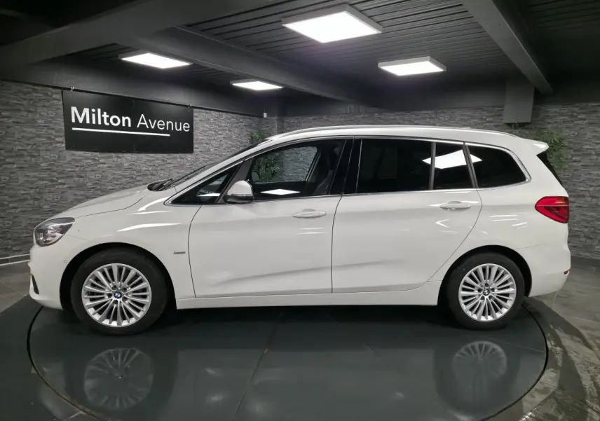 BMW Série 2 Gran Tourer blanc vue de profil côté gauche avec jantes alliage 17 pouces en intérieur showroom