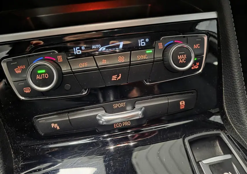 Gros plan sur la console centrale noire brillante avec commandes climatisation et modes de conduite BMW Série 2 Gran Tourer.