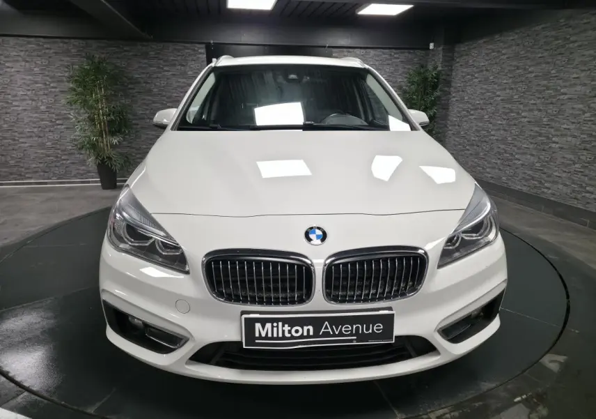 Vue frontale d'une BMW Série 2 Gran Tourer blanche avec calandre chromée et phares LED dans un showroom.