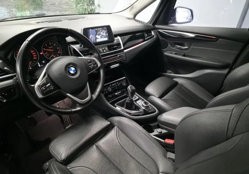 Intérieur BMW Série 2 Gran Tourer vu côté conducteur, sellerie cuir noire et console centrale avec boîte manuelle.