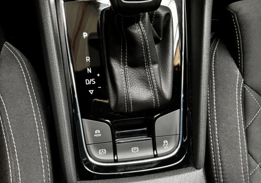 Gros plan sur le levier de vitesses automatique noir marqué SKODA, entouré des sièges et commandes centrales du Skoda Karoq.