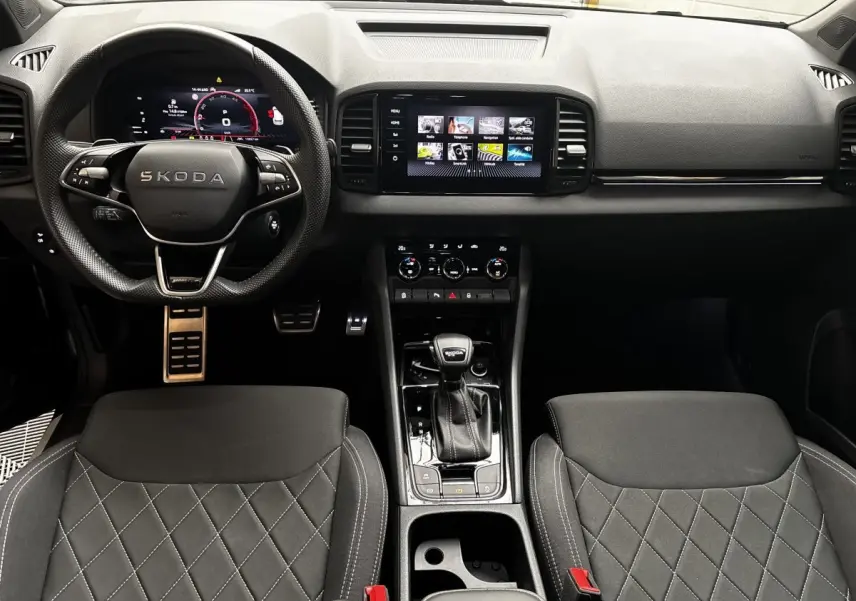 Intérieur noir du Skoda Karoq 2025, vue frontale du tableau de bord avec écran tactile et volant multifonctions.